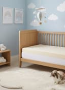 Latex Mattress Topper — cot-size topper on a cot mattress in a sky-and-clouds nursery