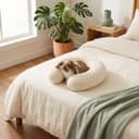 Travel Pillow — cream perforated latex U-pillow resting on a made bed