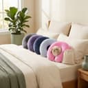 Travel Pillow — the five-colour range with its drawstring travel case, on a bed